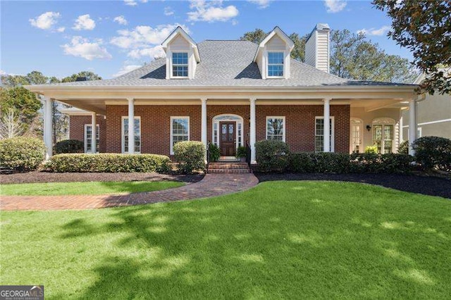 view of front of house featuring brick siding, a chimney, and a front yard