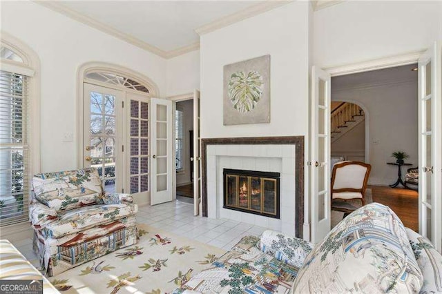 tiled living room featuring a tile fireplace, french doors, and ornamental molding