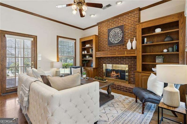 living area with a brick fireplace, wood finished floors, a wealth of natural light, and ceiling fan