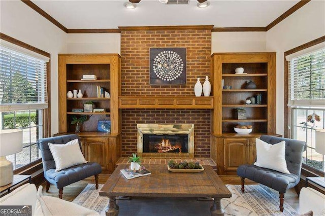 living room with built in shelves, a healthy amount of sunlight, a fireplace, and crown molding