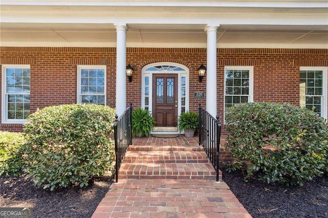 entrance to property featuring a porch and brick siding