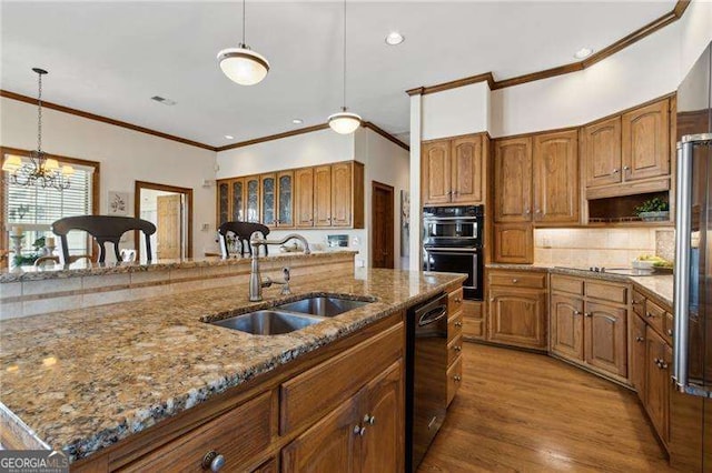 kitchen featuring light stone counters, brown cabinets, a notable chandelier, black appliances, and a sink