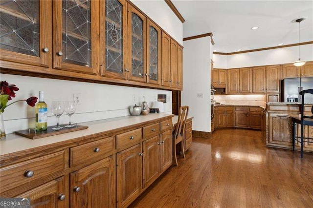 kitchen featuring crown molding, light countertops, dark wood-style floors, stainless steel refrigerator with ice dispenser, and brown cabinetry