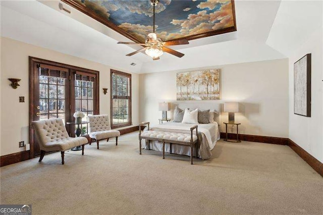 carpeted bedroom with a raised ceiling and baseboards