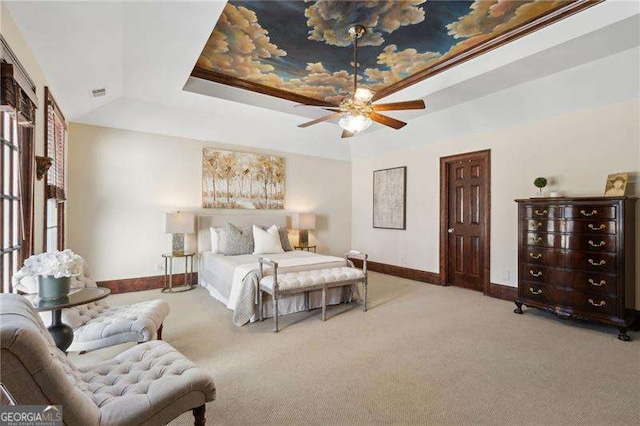 carpeted bedroom with visible vents, a raised ceiling, and baseboards