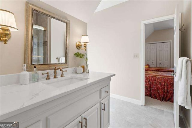 bathroom with vanity, vaulted ceiling, and baseboards