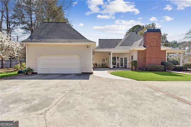 view of front of property with a garage, a front yard, a chimney, and driveway