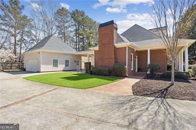 view of front of home featuring brick siding, concrete driveway, a front yard, a chimney, and an attached garage