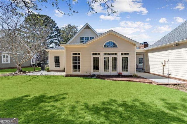 back of property with a patio, a yard, and french doors