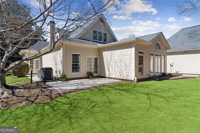 rear view of house with a yard, a patio, central AC unit, and a chimney