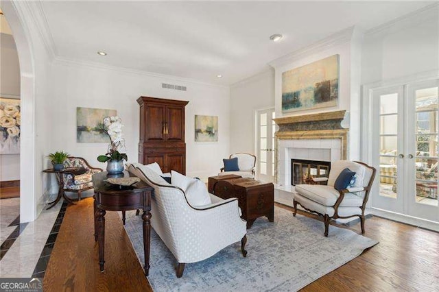 living room featuring visible vents, arched walkways, a tile fireplace, ornamental molding, and french doors