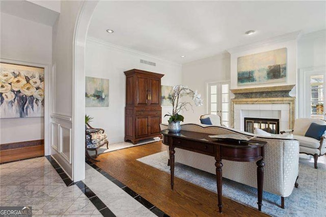 living area featuring visible vents, crown molding, baseboards, a multi sided fireplace, and arched walkways