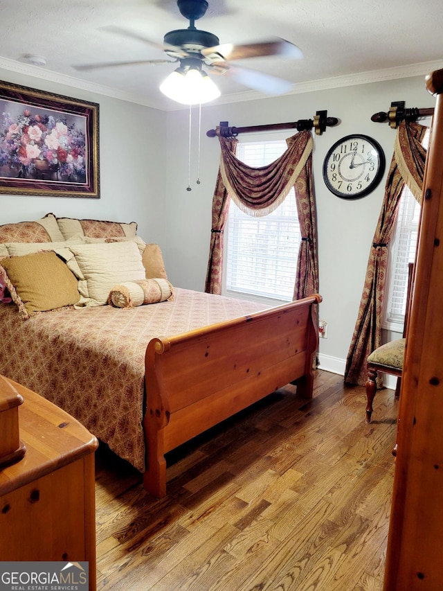 bedroom featuring ceiling fan, baseboards, wood finished floors, and crown molding