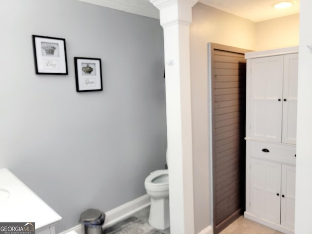 bathroom featuring crown molding, toilet, baseboards, and ornate columns