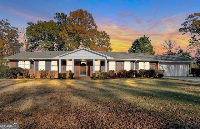 ranch-style house featuring a front lawn, an attached garage, brick siding, and driveway