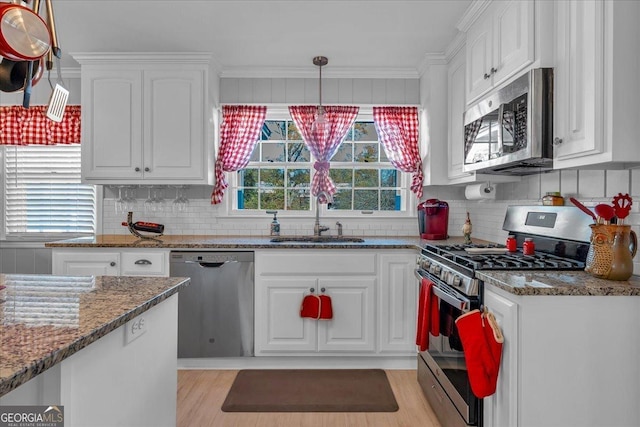 kitchen featuring a sink, dark stone countertops, white cabinets, and stainless steel appliances