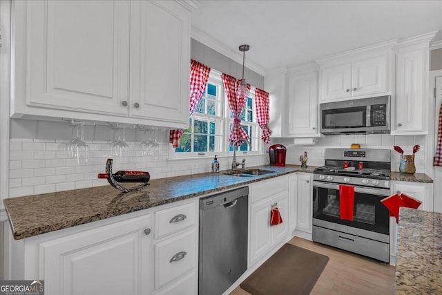 kitchen with dark stone counters, a sink, white cabinets, appliances with stainless steel finishes, and tasteful backsplash