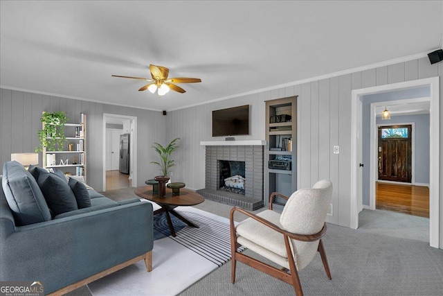 living area featuring a fireplace, carpet, ceiling fan, and ornamental molding