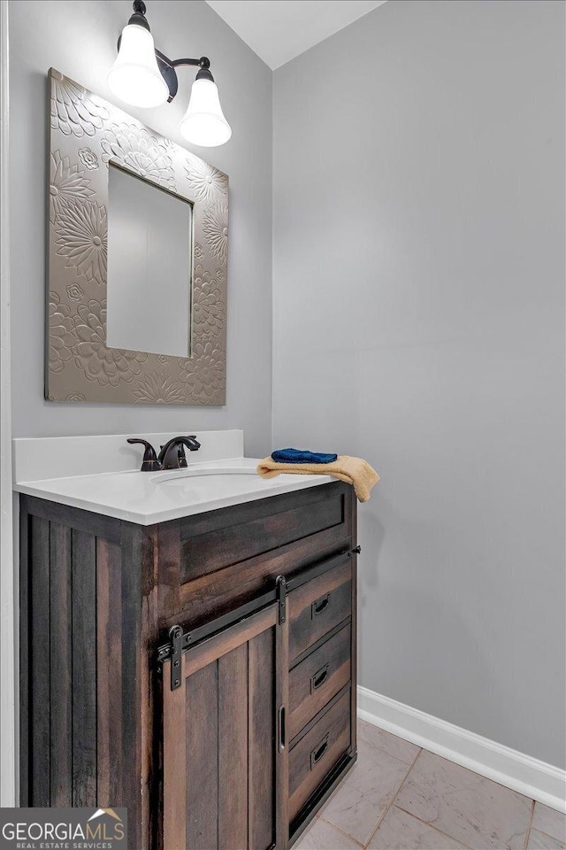 bathroom with marble finish floor, vanity, and baseboards