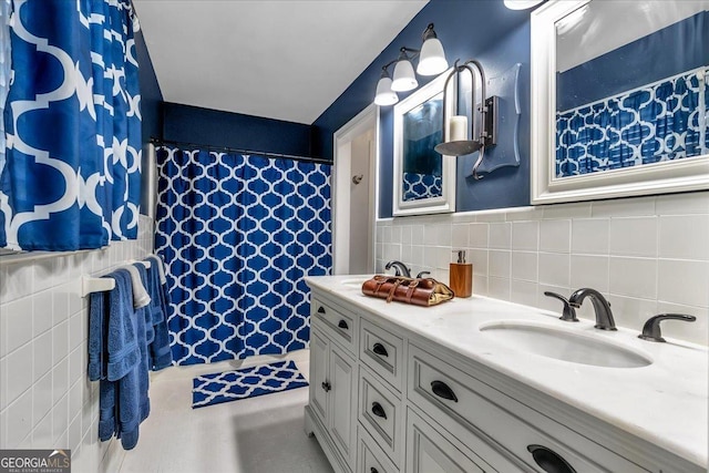 full bath with a sink, a shower with shower curtain, and tile walls