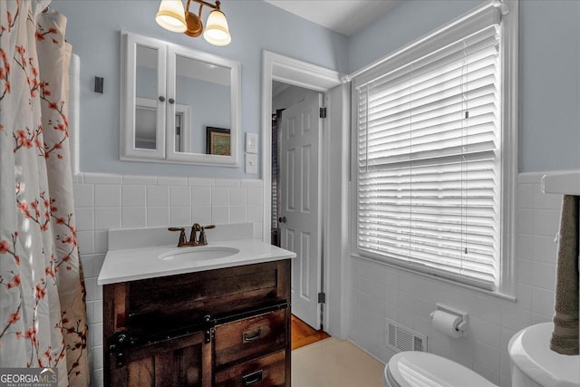 full bathroom with vanity, visible vents, wainscoting, tile walls, and toilet