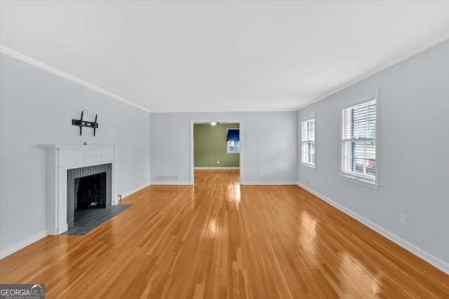 unfurnished living room featuring baseboards, light wood-style flooring, a fireplace, and crown molding