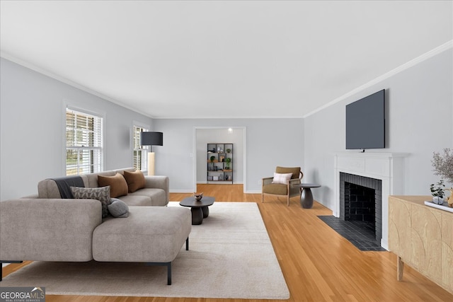 living area with a brick fireplace, light wood-style floors, baseboards, and ornamental molding