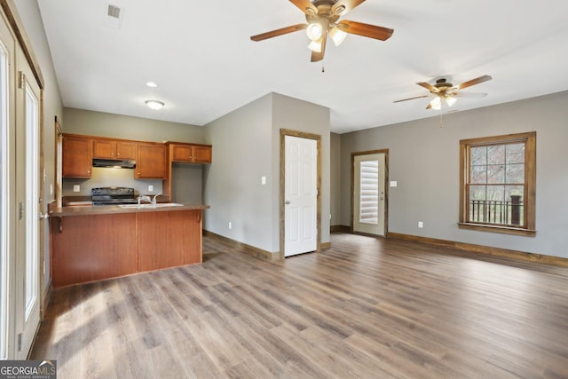 kitchen featuring ceiling fan, a peninsula, under cabinet range hood, and range with electric cooktop