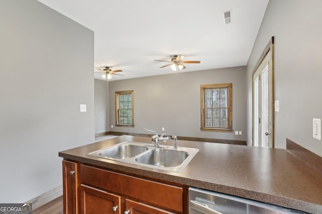 kitchen featuring dark countertops, a sink, open floor plan, a ceiling fan, and stainless steel dishwasher