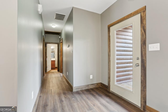 hall featuring visible vents, baseboards, and wood finished floors