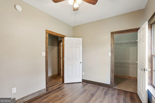 unfurnished bedroom featuring a closet, baseboards, wood finished floors, and a ceiling fan