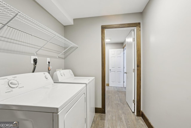 laundry room featuring baseboards, washing machine and dryer, laundry area, and light wood finished floors