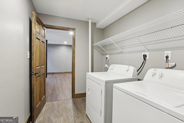 laundry room featuring baseboards, wood finished floors, laundry area, and washer and clothes dryer