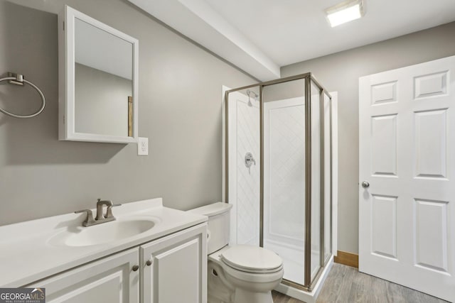 full bath with a shower stall, vanity, toilet, and wood finished floors