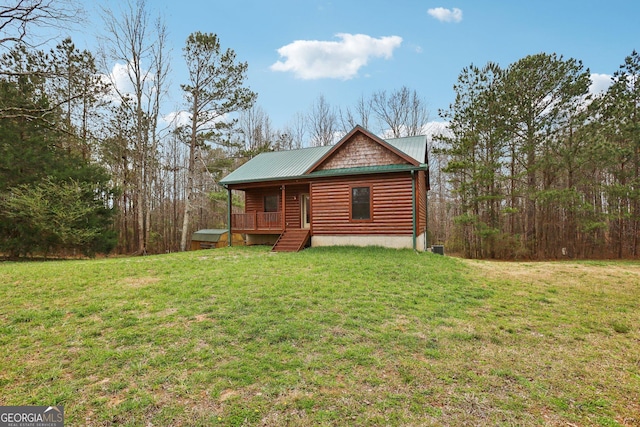 exterior space featuring log veneer siding, a front yard, and metal roof