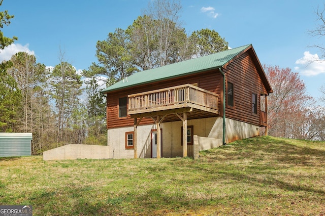 rear view of property with a yard, metal roof, and a wooden deck