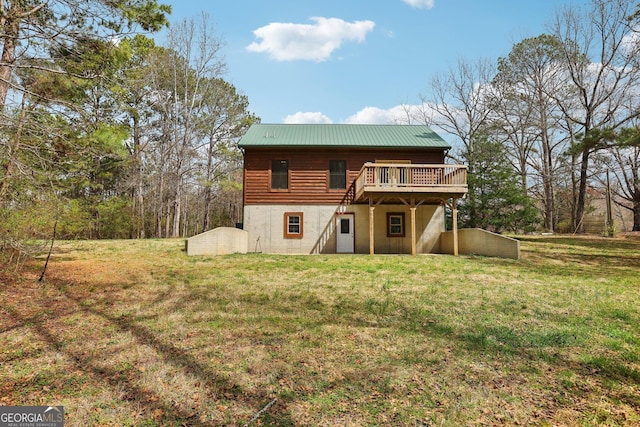 rear view of property featuring a lawn, metal roof, and a deck