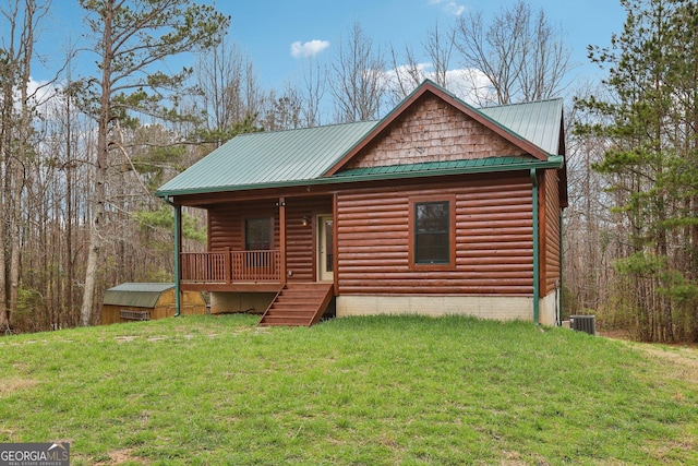 cabin with log veneer siding, covered porch, a front yard, metal roof, and central AC unit