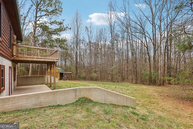 view of yard featuring a forest view and a wooden deck