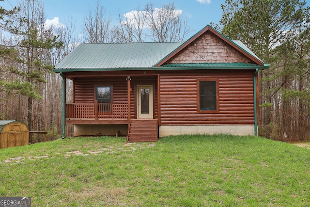 log home with a porch, a front yard, metal roof, a storage shed, and an outdoor structure