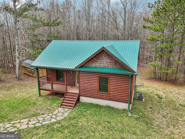 view of front of property with faux log siding, a front yard, central air condition unit, and metal roof