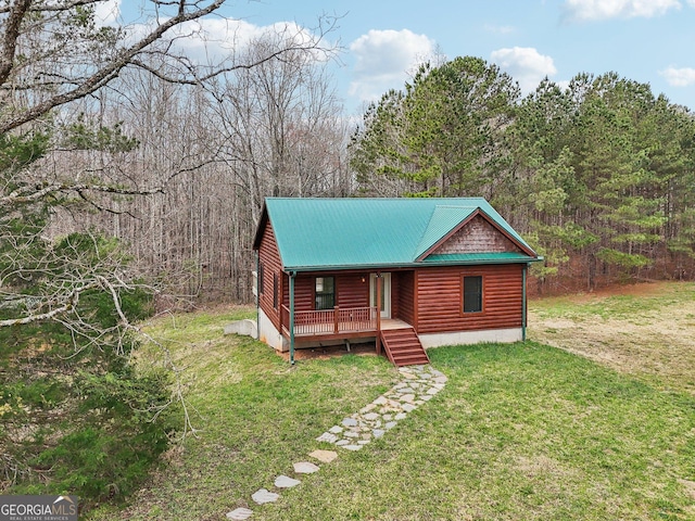 rustic home featuring log veneer siding, metal roof, a front lawn, and a view of trees