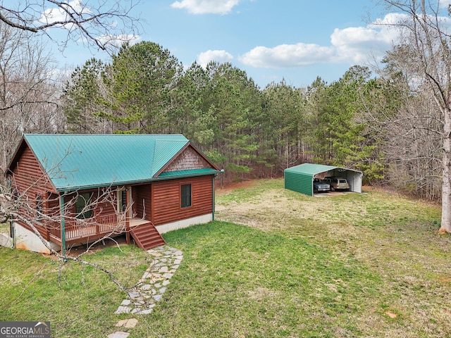 chalet / cabin featuring a porch, a carport, a front lawn, a view of trees, and metal roof