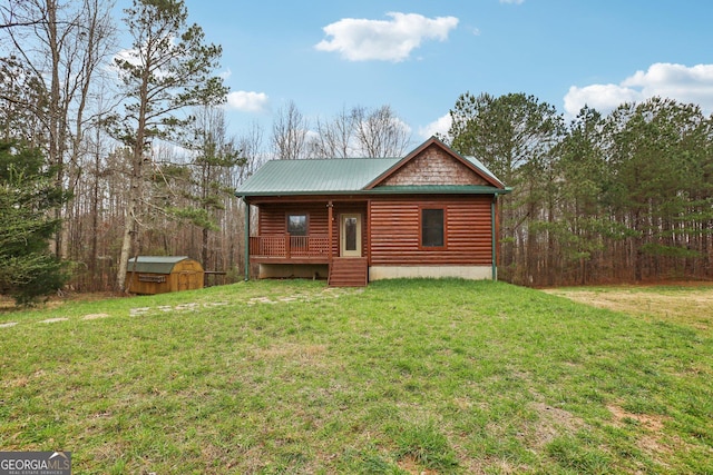 back of house with faux log siding, covered porch, a yard, an outdoor structure, and a storage unit