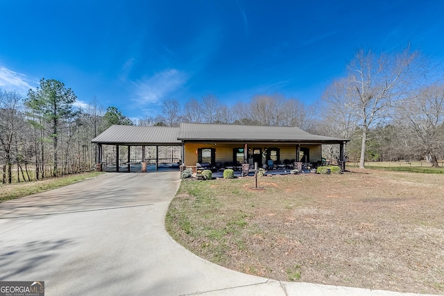 view of front of property featuring a carport, driveway, and metal roof