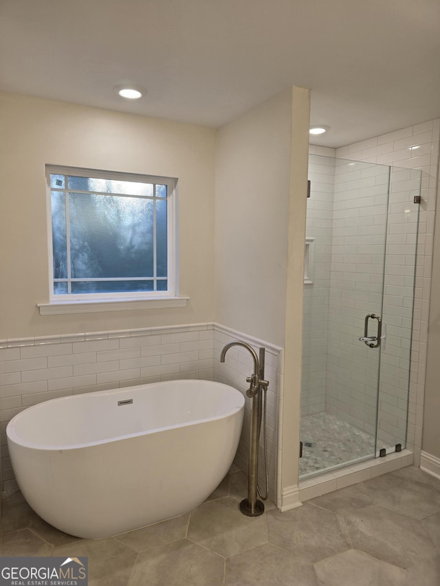 bathroom with a wainscoted wall, a freestanding bath, recessed lighting, a stall shower, and tile patterned floors