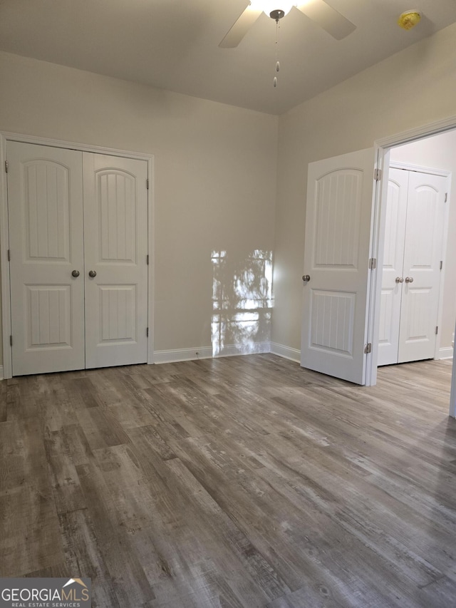 unfurnished bedroom with ceiling fan, a closet, baseboards, and wood finished floors