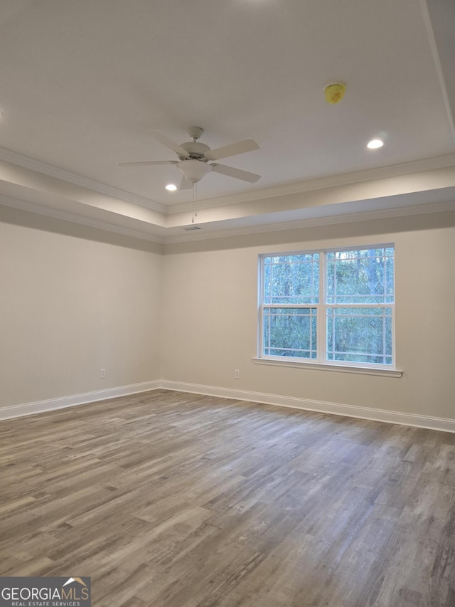 unfurnished room with a ceiling fan, a raised ceiling, wood finished floors, and baseboards