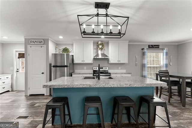 kitchen featuring a sink, stainless steel appliances, wall chimney exhaust hood, crown molding, and white cabinets