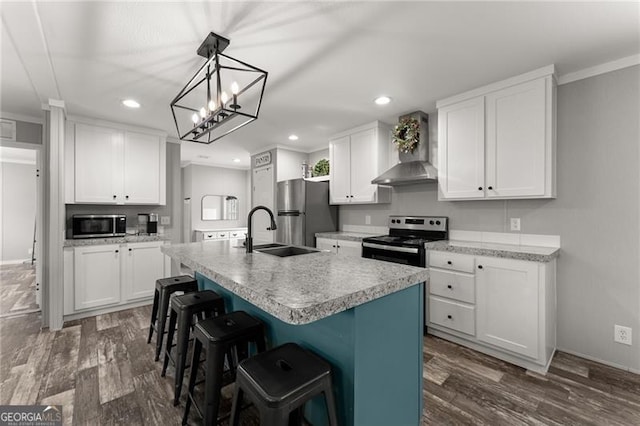 kitchen featuring a sink, wall chimney range hood, dark wood-style floors, stainless steel appliances, and light countertops